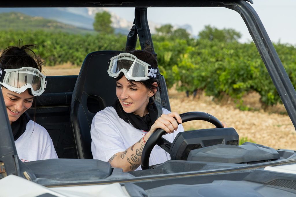 Dos ocupantes con gafas de protección en un buggy entre viñedos